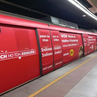 Zomato-themed metro train with bright red branding and food slogans at a subway platform.