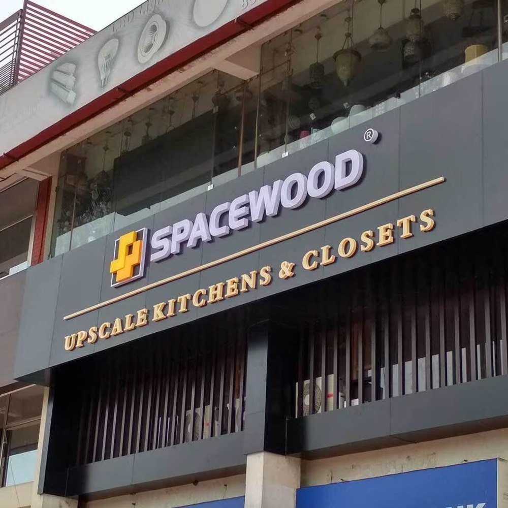 Modern commercial building facade featuring a large 3D acrylic and metal signage board for a kitchen and closet showroom, mounted above a glass-fronted retail space.